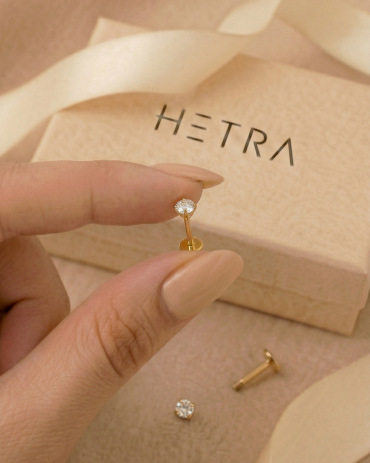 Altın renkli 316L cerrahi çelik 6 mm tektaş flatback tragus piercing tasarımın elde duruşu.