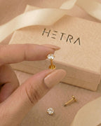 Altın renkli 316L cerrahi çelik 6 mm zirkon taşlı flatback tragus piercing tasarımın elde duruşu.