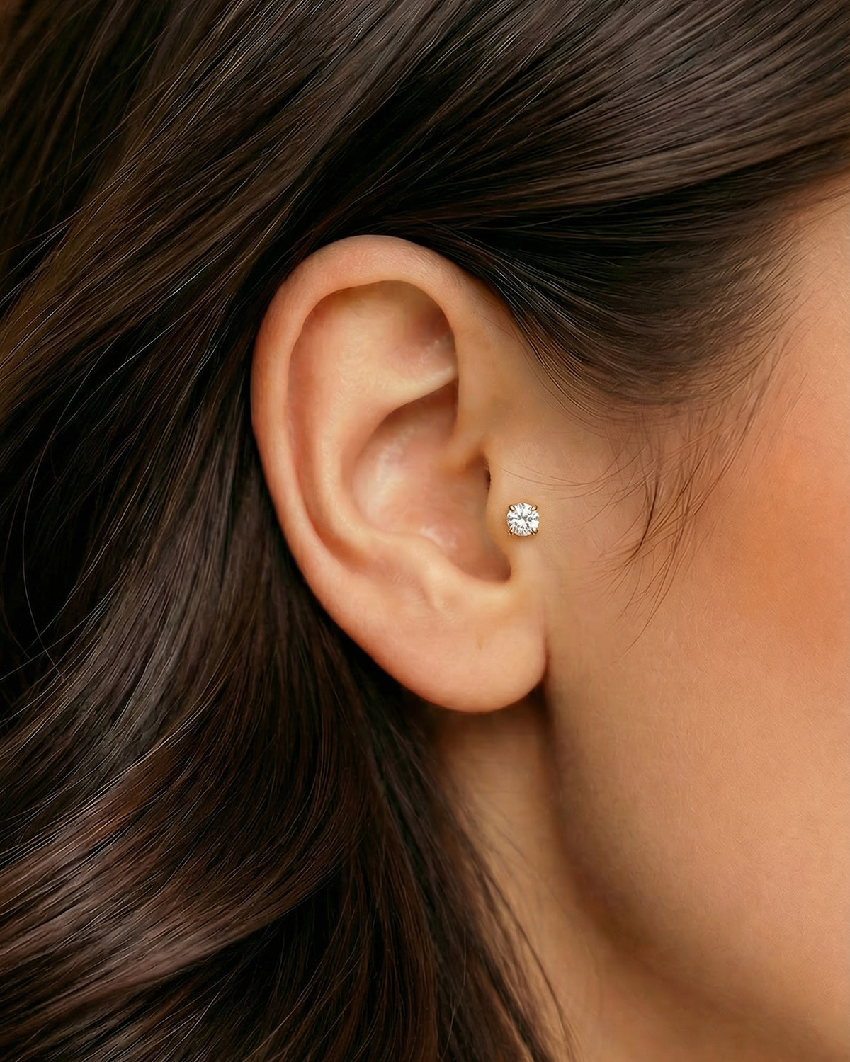 Altın renkli 8 mm zirkon taşlı flatback piercingin tragus ve kıkırdakta duruşu.