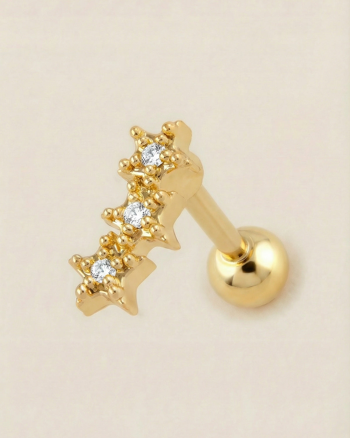 Altın renkli 316L cerrahi çelik üçlü yıldız formlu zirkon taşlı tragus piercing tasarımı.