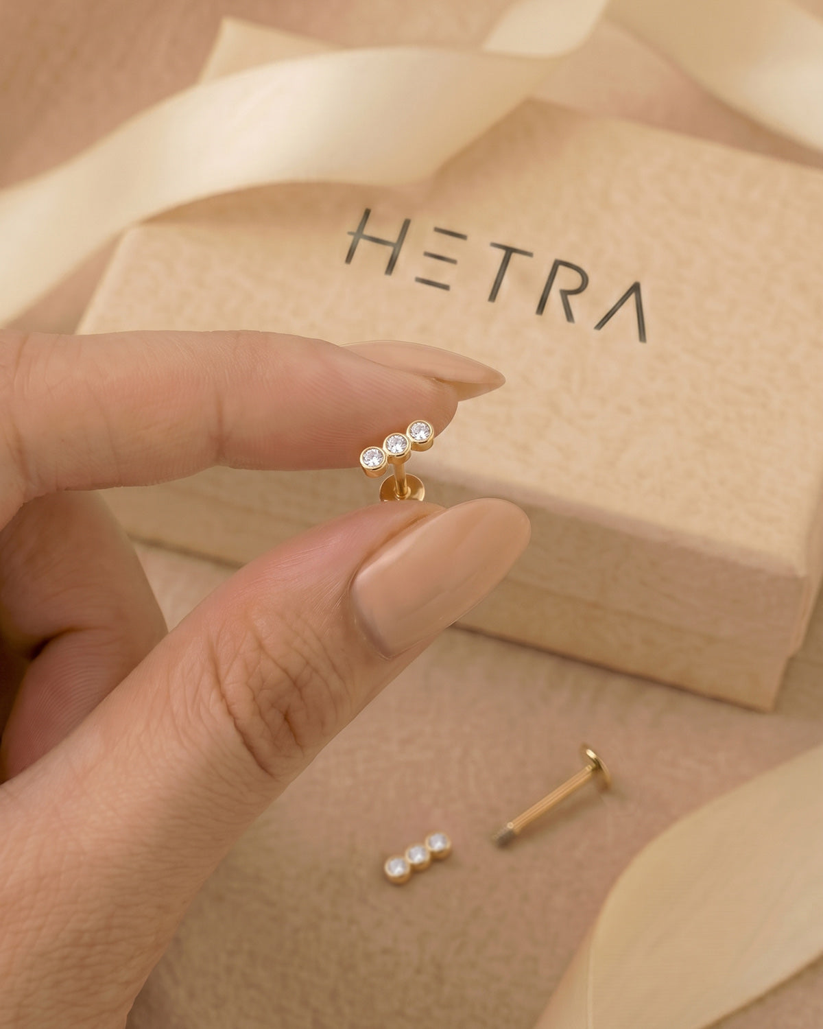 Altın renkli sıralı 3 taşlı flatback piercingin eldeki görünümü ve gerçek boyutu.