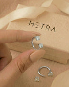 Gümüş renkli 316L cerrahi çelik 10 mm çift tektaş yarım halka piercing tasarımın elde duruşu.
