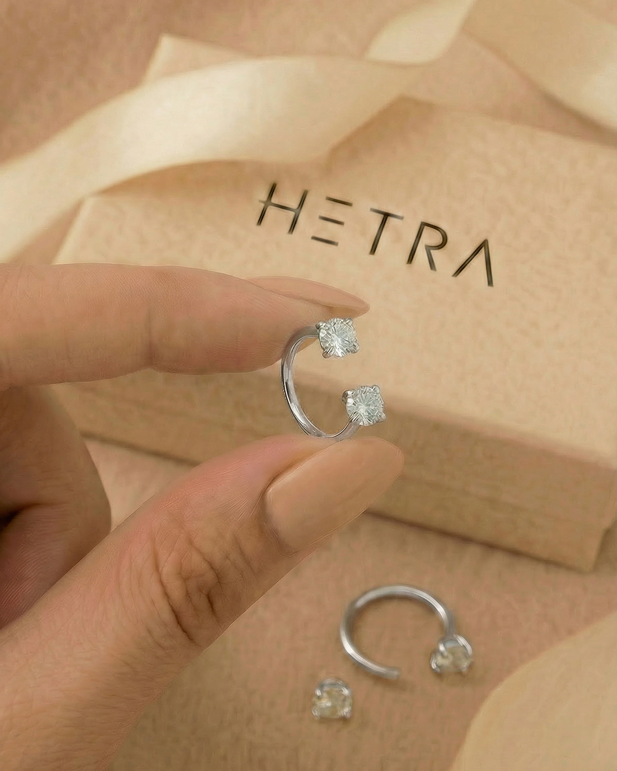 Gümüş renkli 316L cerrahi çelik 10 mm çift tektaş yarım halka piercing tasarımın elde duruşu.