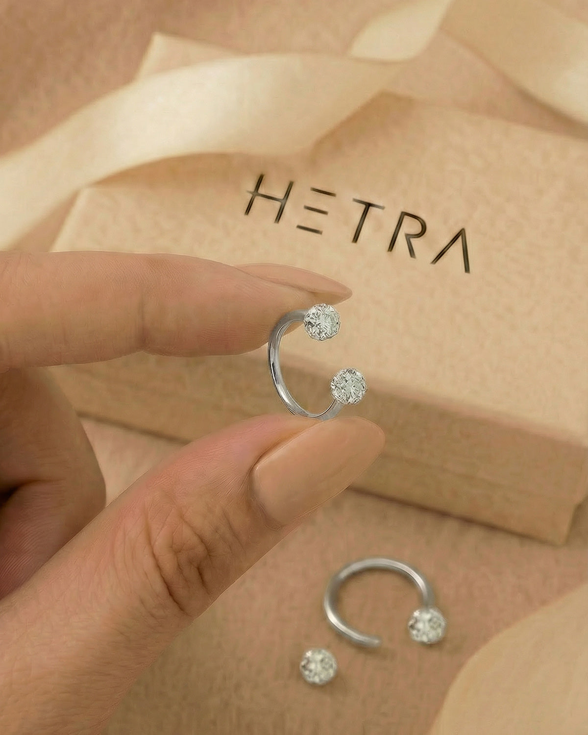Gümüş renkli 316L cerrahi çelik 10 mm zirkon taşlı yarım halka piercing tasarımın elde duruşu.