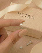 Gümüş renkli 316L cerrahi çelik 6 mm tektaş flatback tragus piercing tasarımın elde duruşu.