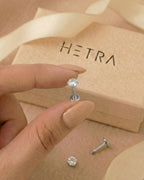 Gümüş renkli 316L cerrahi çelik 6 mm zirkon taşlı flatback tragus piercing tasarımın elde duruşu.