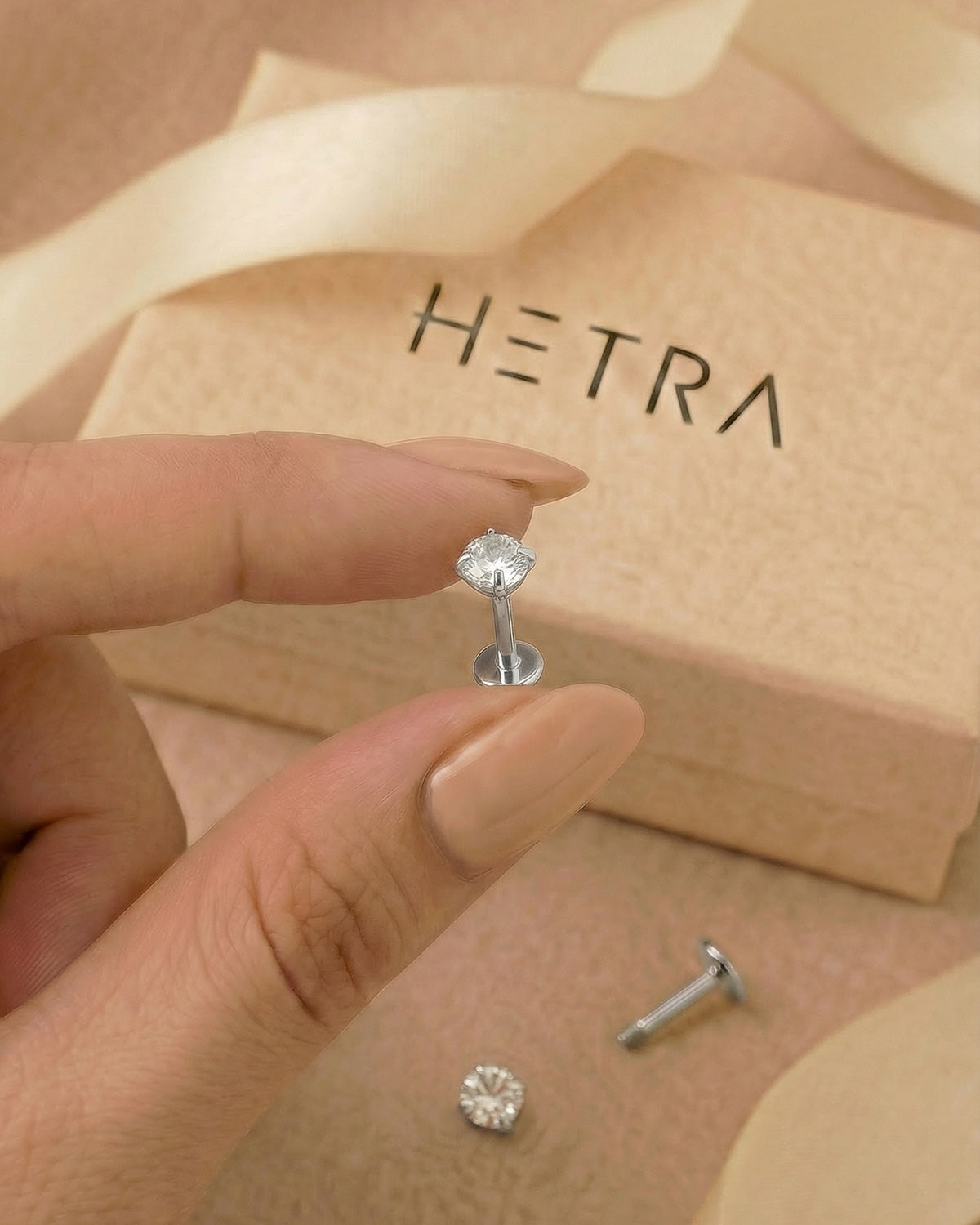 Gümüş renkli 316L cerrahi çelik 6 mm zirkon taşlı flatback tragus piercing tasarımın elde duruşu.