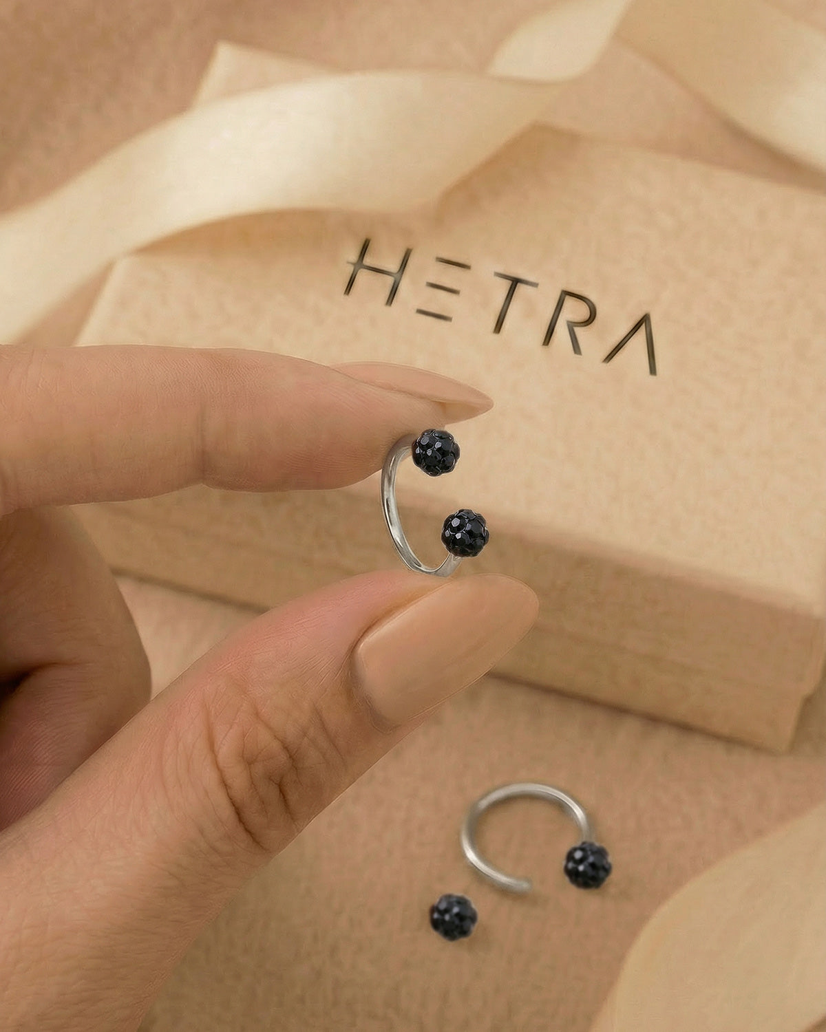 Gümüş renkli siyah toplu 316L cerrahi çelik 8 mm zirkon taşlı yarım halka piercing tasarımın elde duruşu.