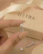 Gümüş renkli 316L cerrahi çelik 8 mm zirkon taşlı flatback tragus piercing tasarımın elde duruşu.