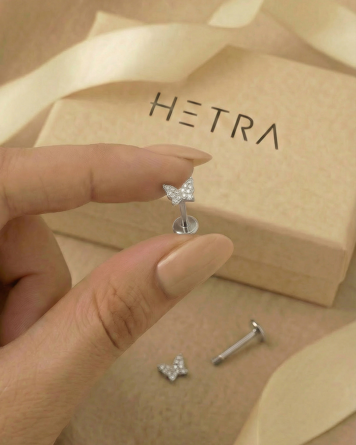 Pave zirkon taşlı kelebek gümüş renkli flatback piercingin elde gerçek boyutu.