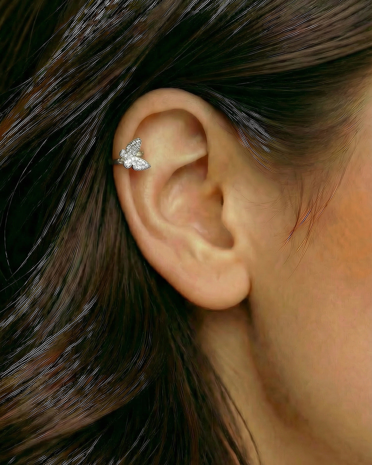 Gümüş renkli pave zirkon taşlı kelebek halka piercingin helix ve kıkırdak bölgesinde duruşu.