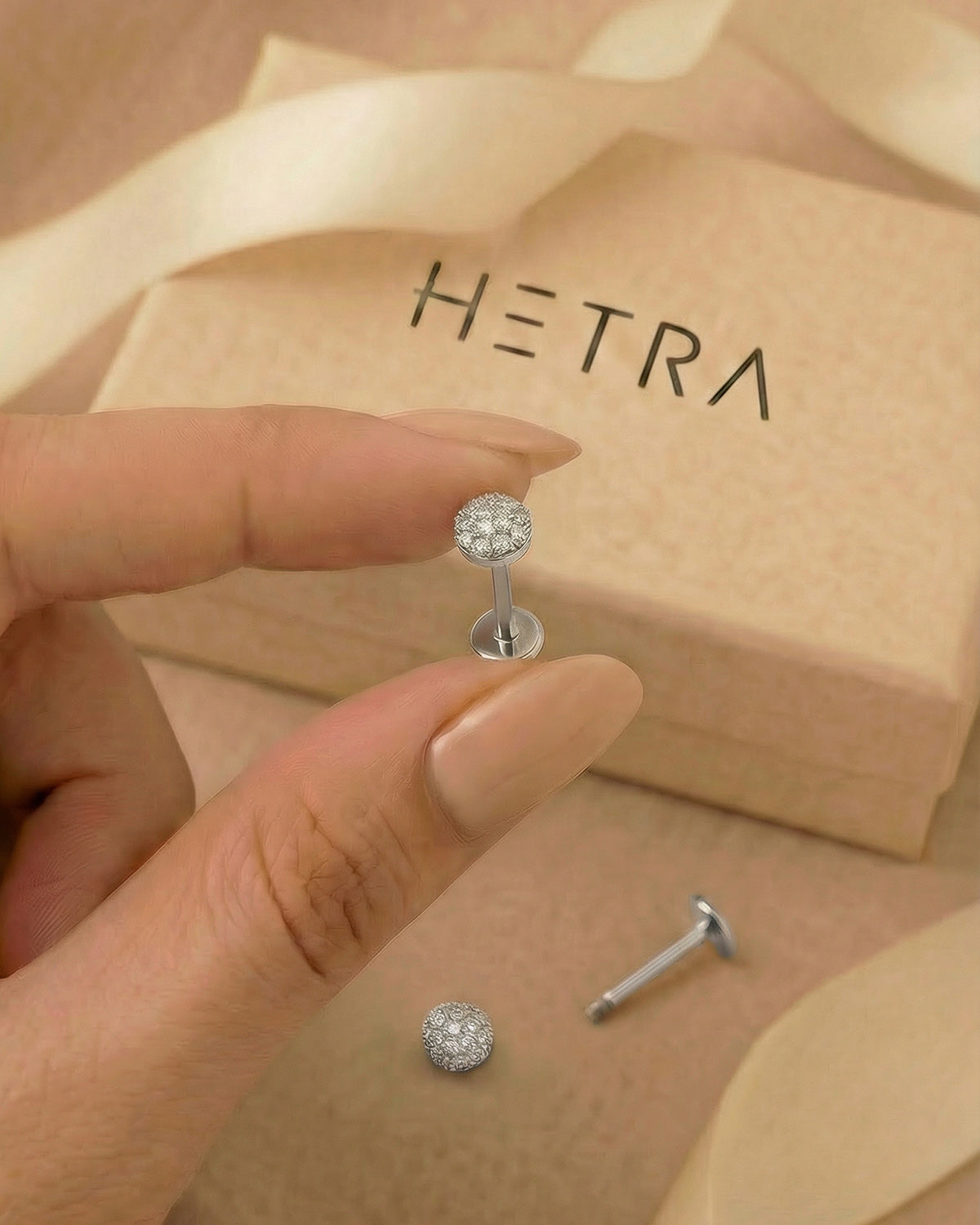 Pave zirkon taşlı yarım küre gümüş renkli flatback piercingin elde boyutu.