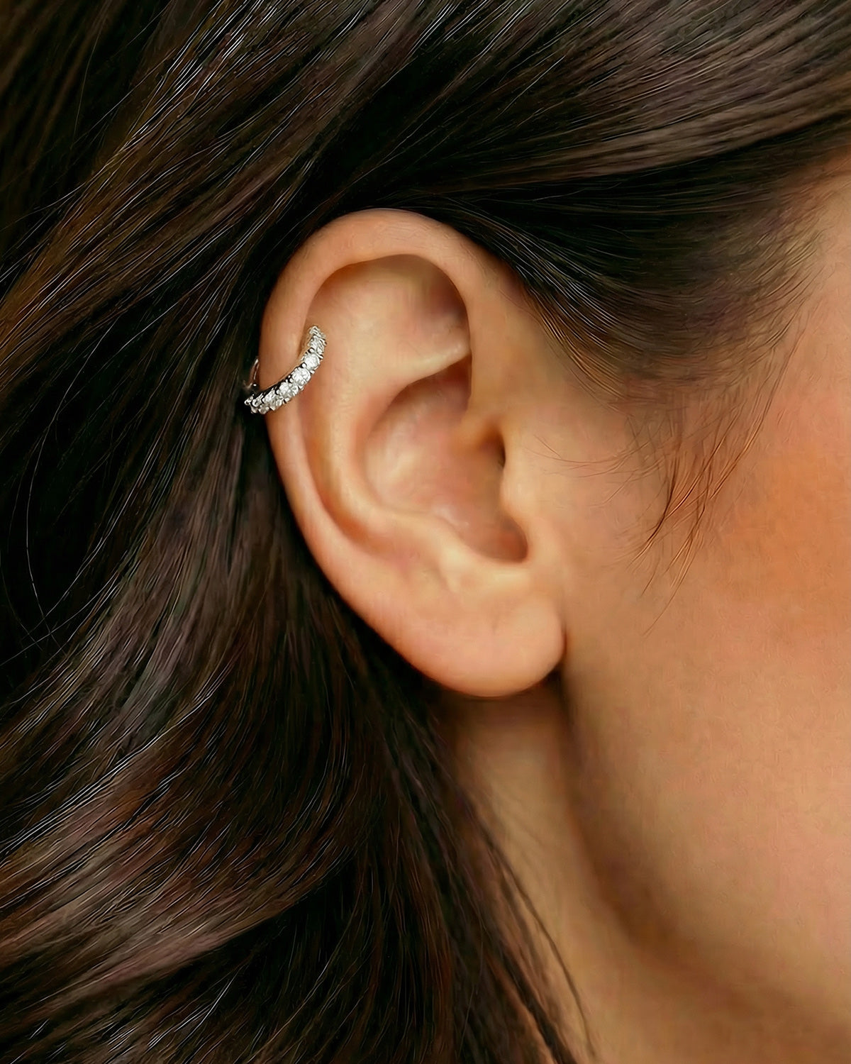 Gümüş renkli tek sıra zirkon taşlı halka piercingin helix ve kıkırdak bölgesinde duruşu.