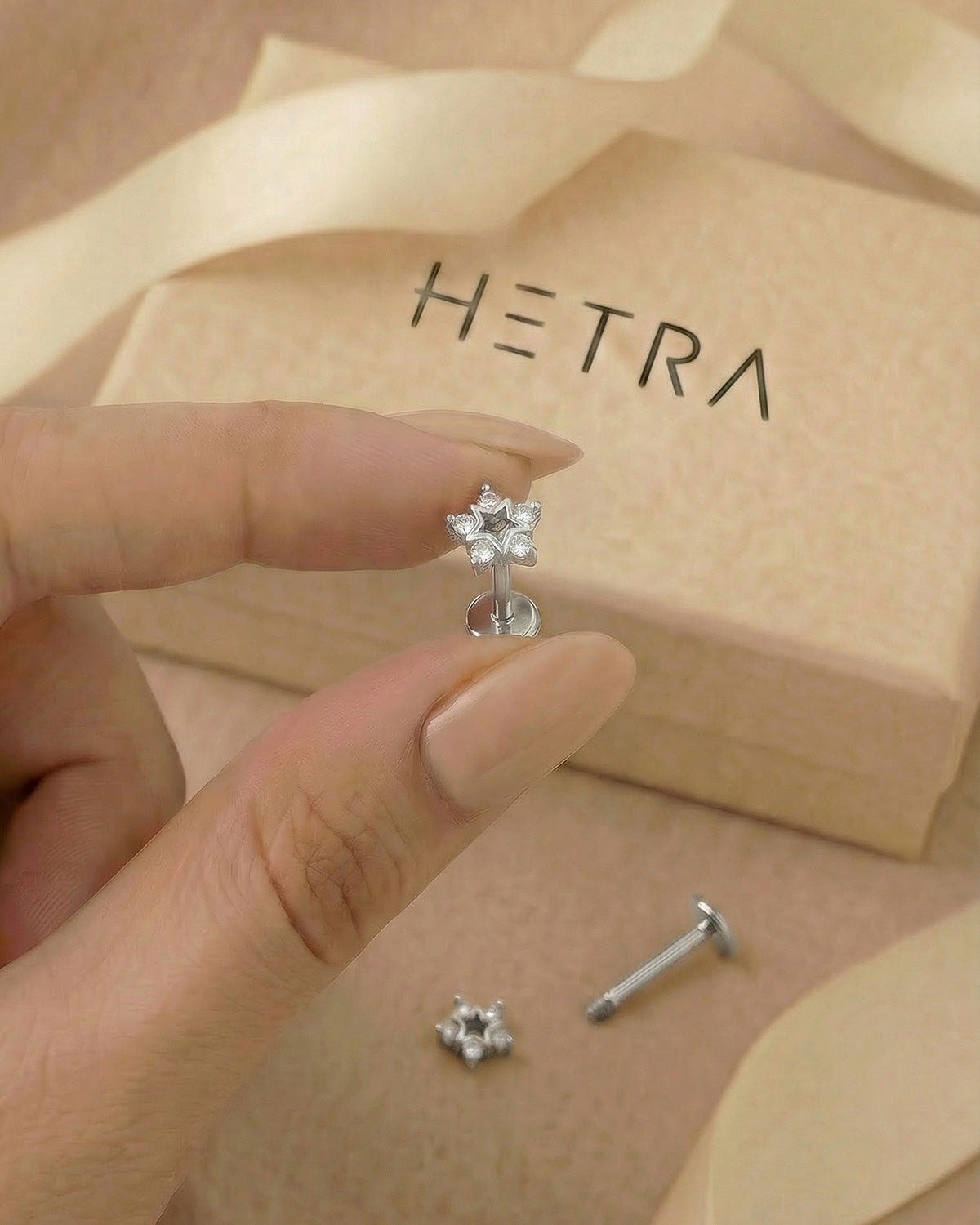 Zirkon taşlı beş köşeli yıldız gümüş renkli flatback piercingin elde boyutu.