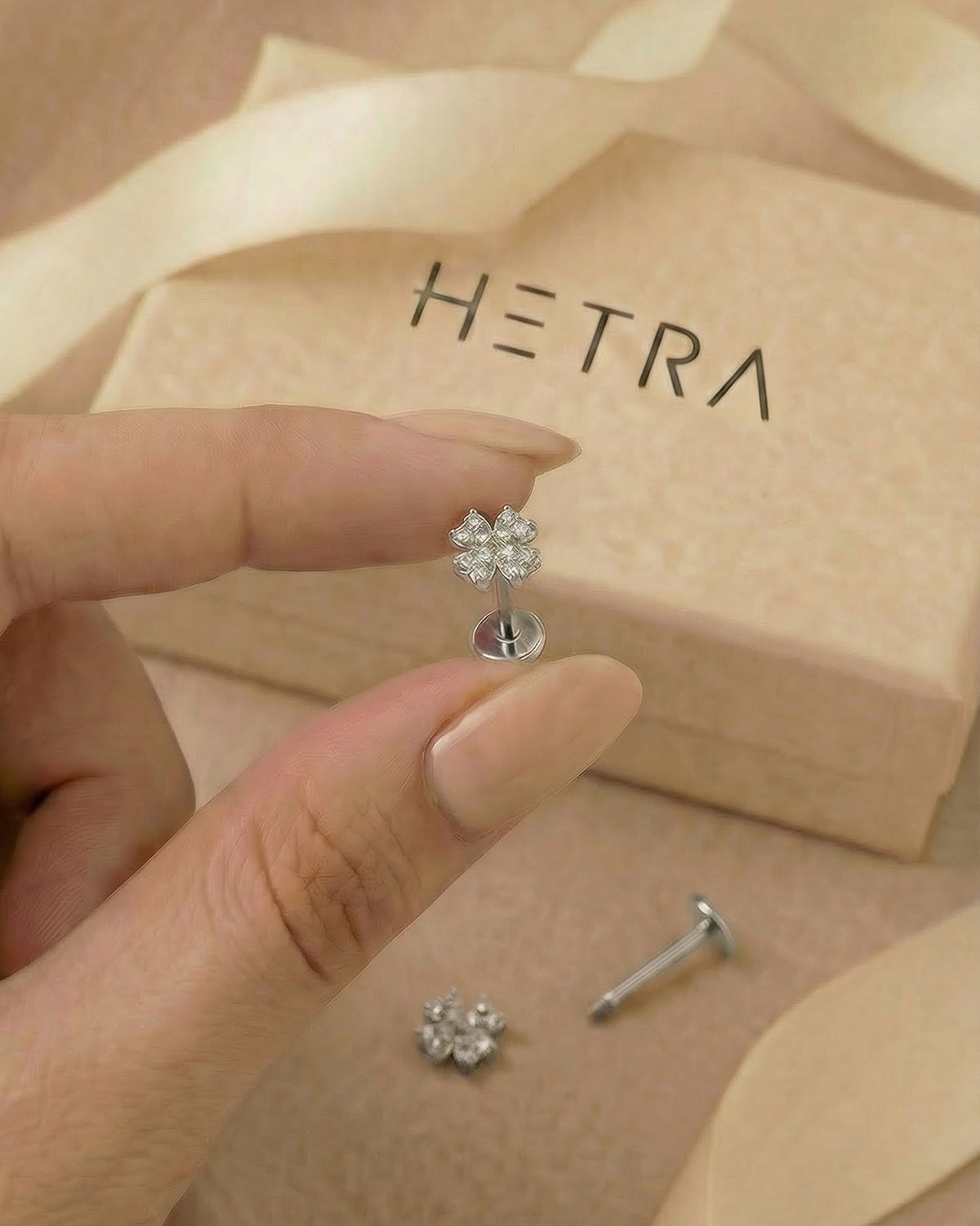Zirkon taşlı dört yapraklı yonca gümüş renkli flatback piercingin elde boyutu.