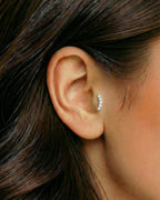 Gümüş renkli zirkon taşlı minimal kavisli piercingin tragus ve helix bölgesinde duruşu.