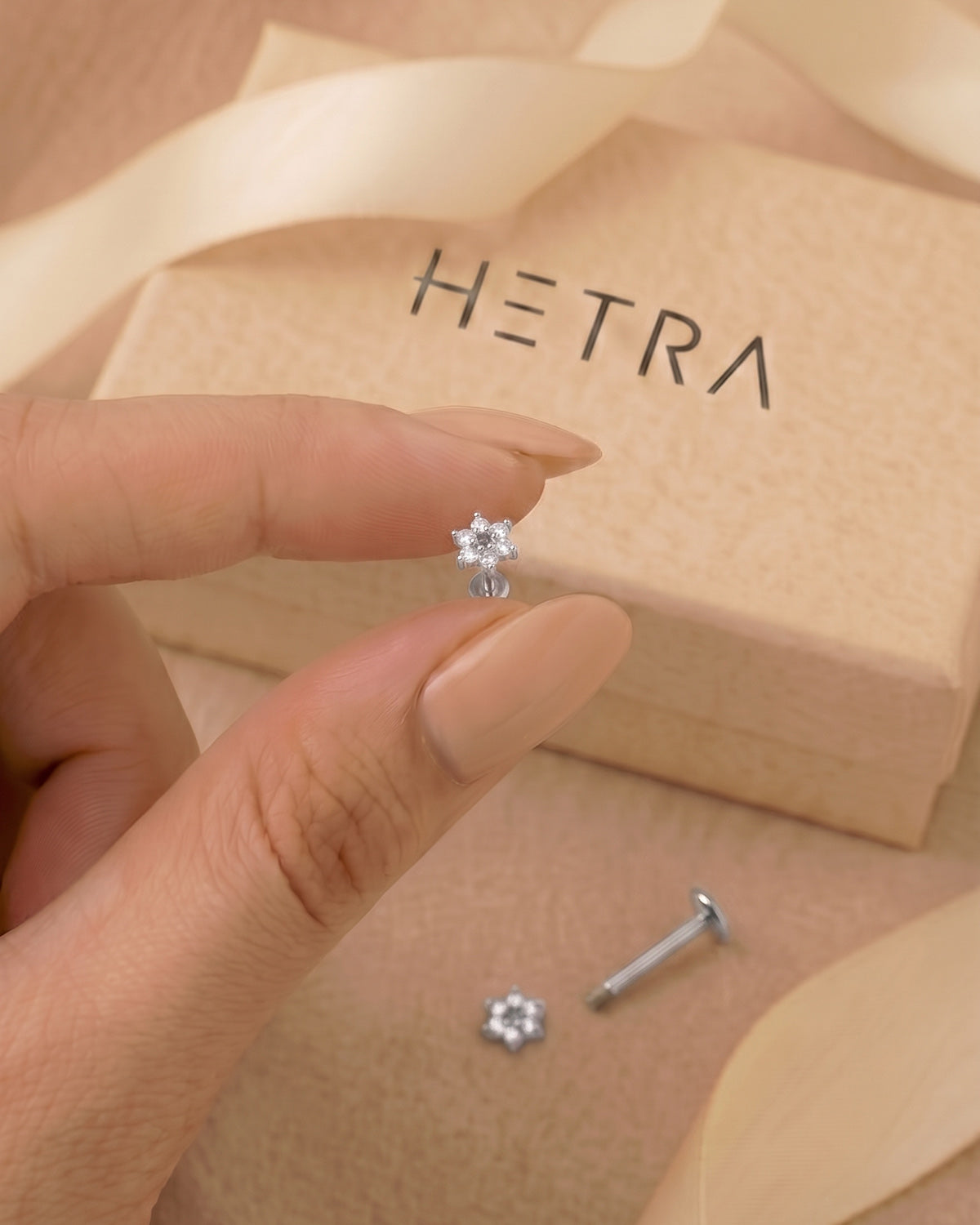 Gümüş renkli çiçek flatback piercingin eldeki görünümü ve gerçek boyutu.
