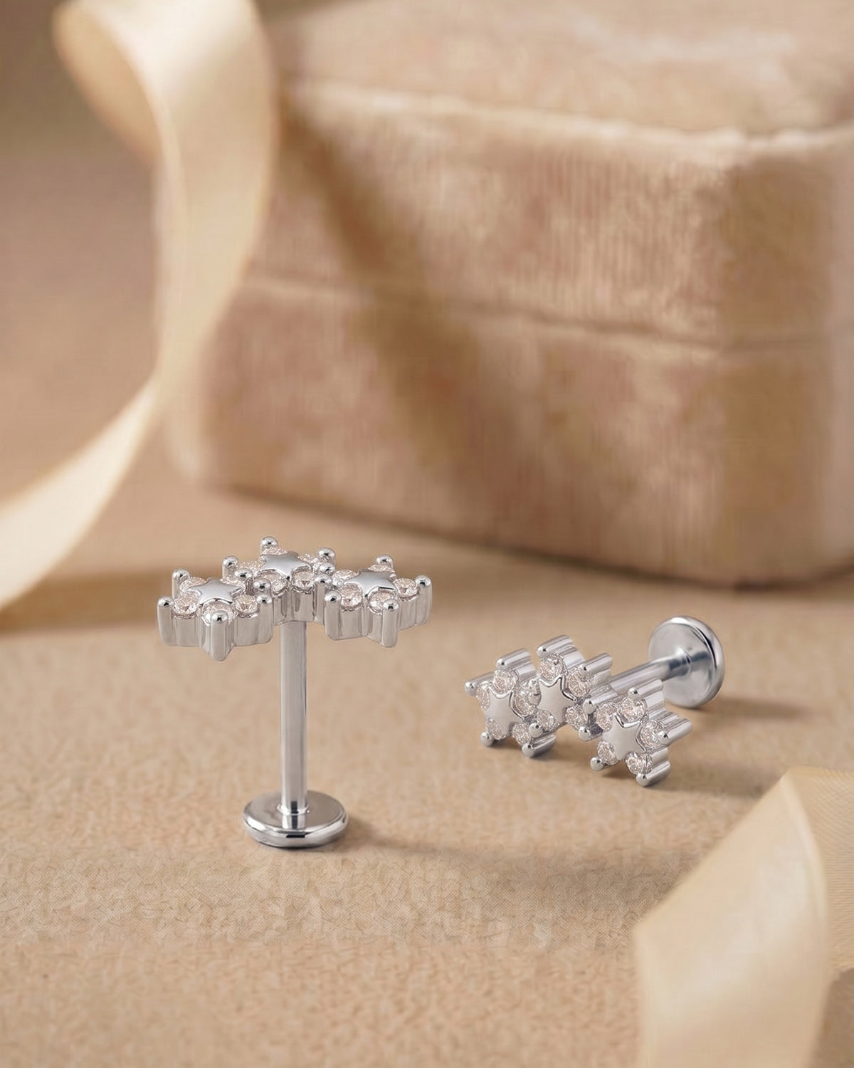 Gümüş renkli kavisli 3 çiçek formlu flatback piercingin koleksiyon görünümü.