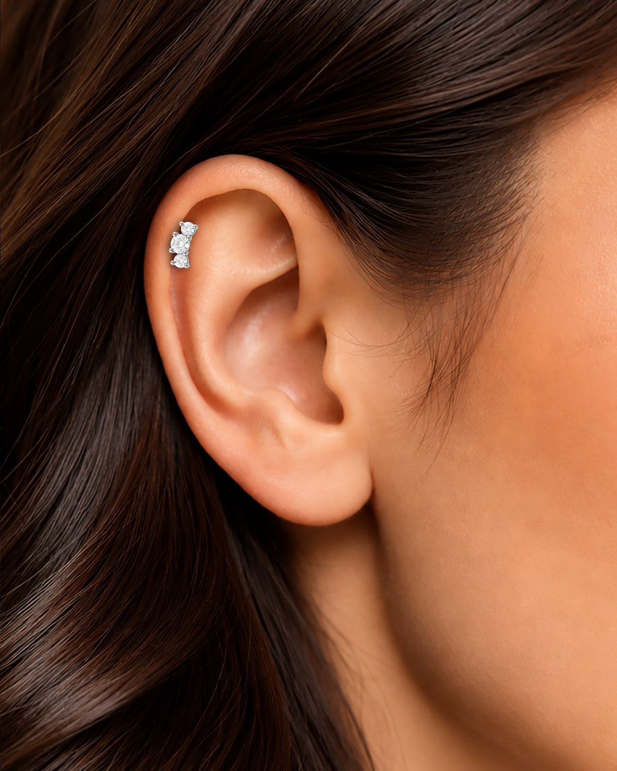 Gümüş renkli kavisli büyük 3 taşlı flatback piercingin tragus ve helix bölgesindeki duruşu.