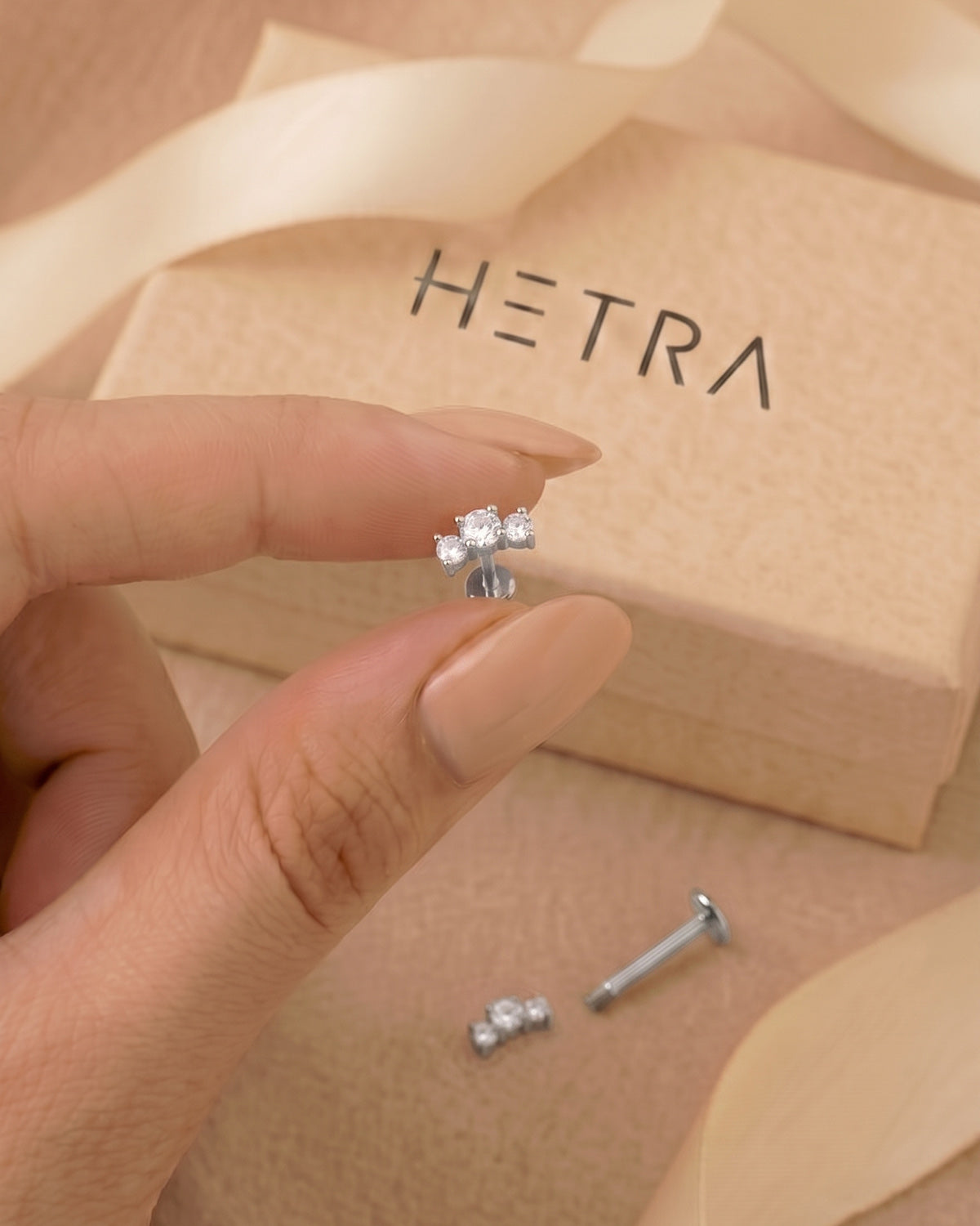 Gümüş renkli kavisli büyük 3 taşlı flatback piercingin eldeki görünümü ve gerçek boyutu.