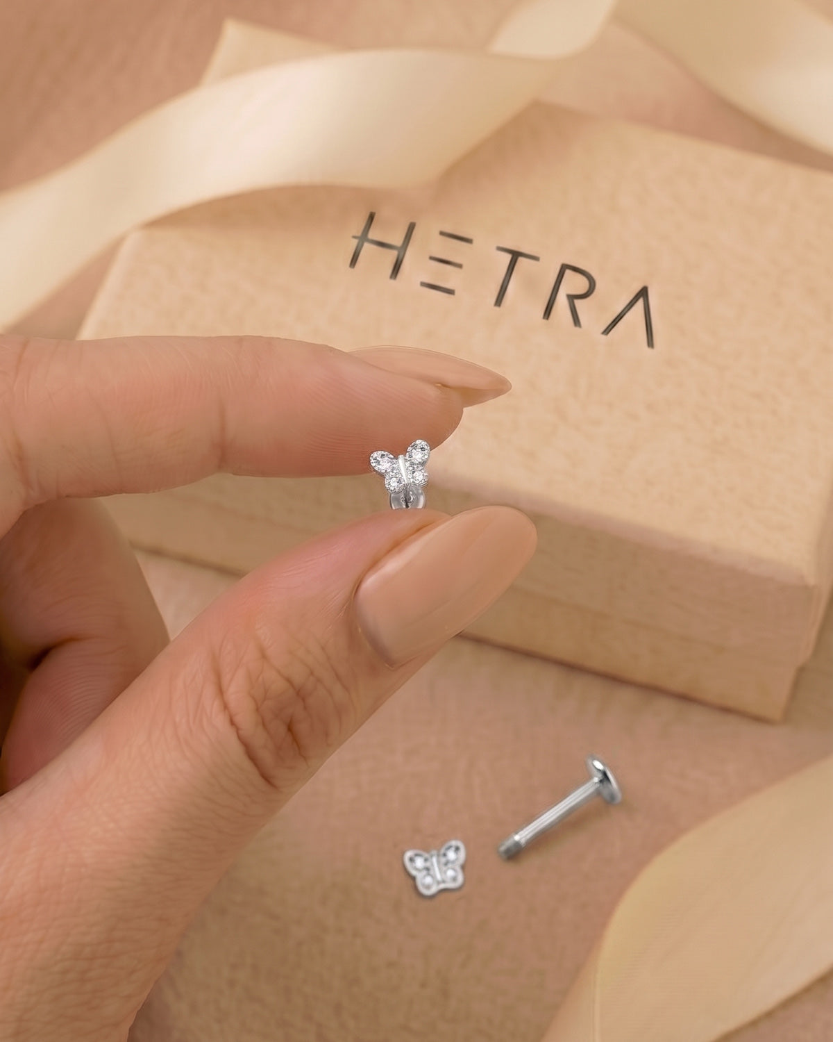 Gümüş renkli kelebek figürlü flatback piercingin eldeki görünümü ve gerçek boyutu.