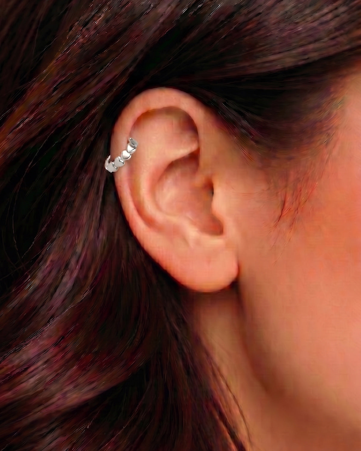 Gümüş renkli sıralı kalp figürlü halka piercingin helix ve kıkırdak bölgesindeki duruşu.