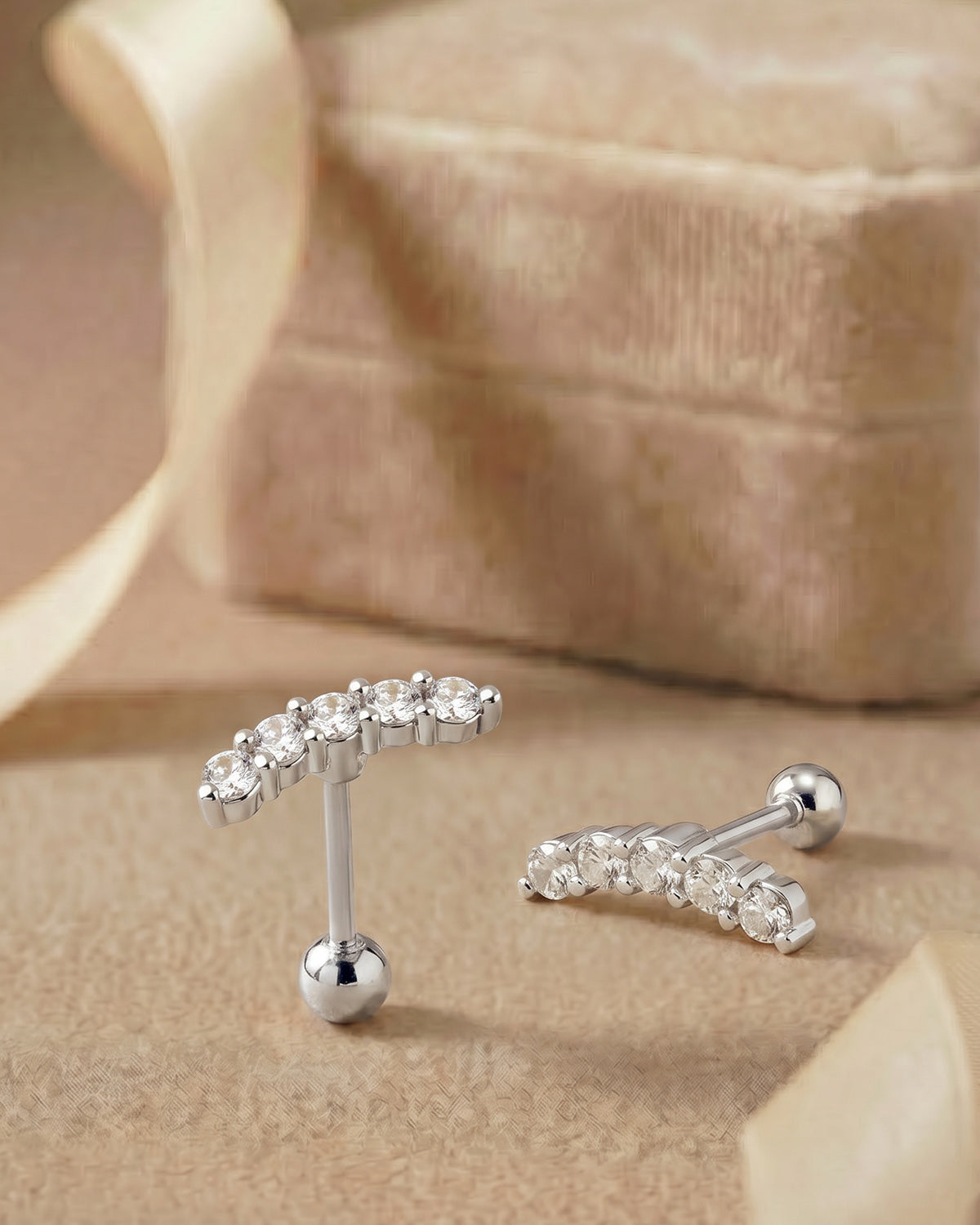 Gümüş renkli zirkon taşlı kavisli tragus piercingin koleksiyon görünümü.